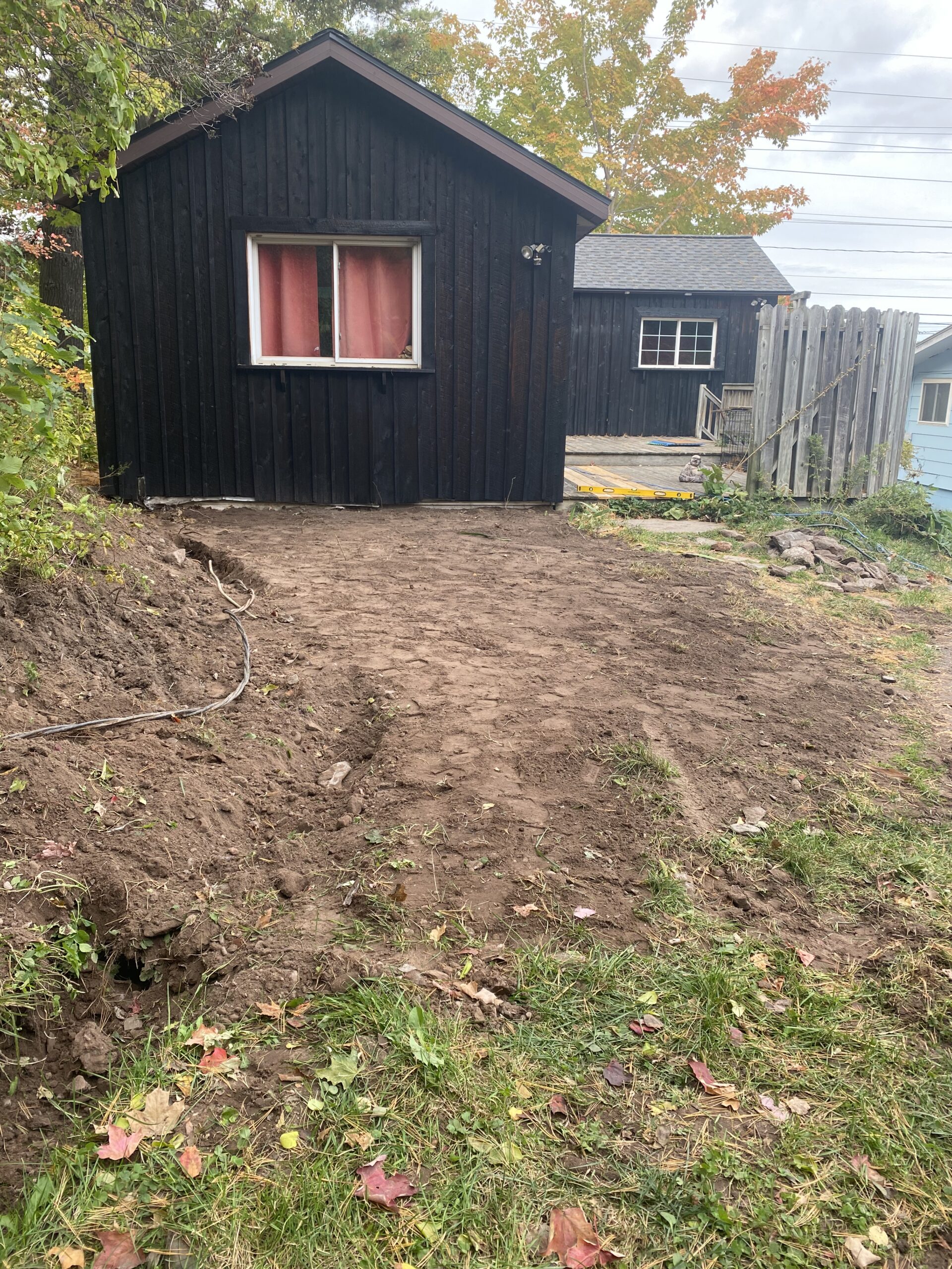 Dirt pile next to an open trench with utility pipes.